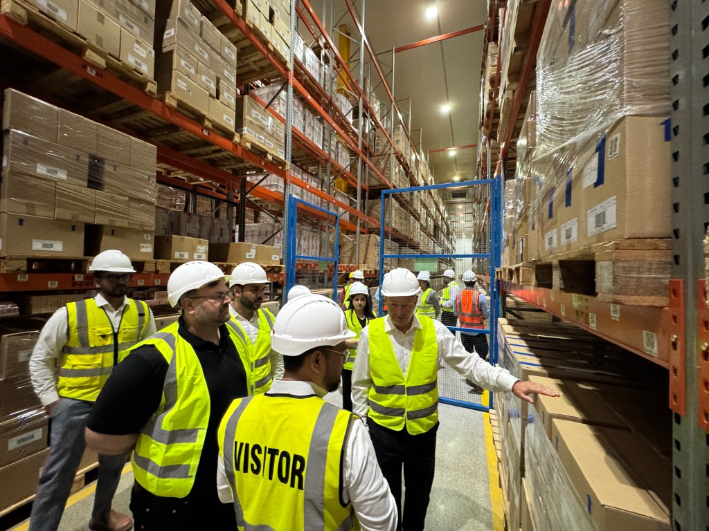 Reckitt leadership inspecting palletised stock and racking systems during the warehouse tour
