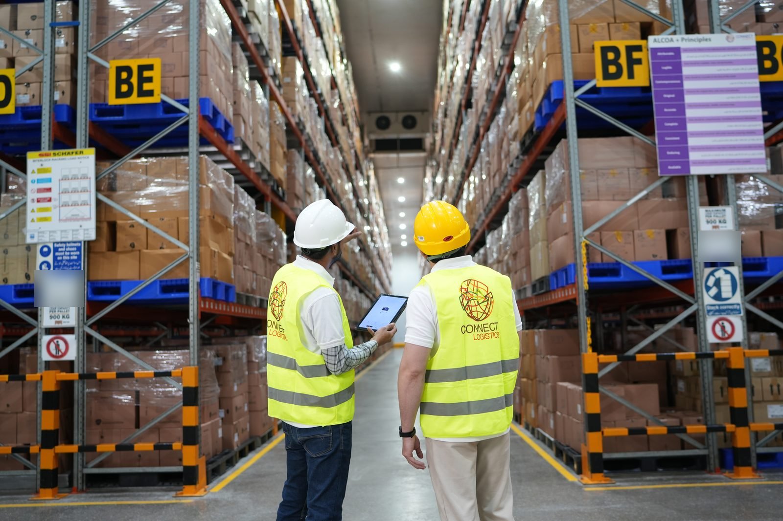 Warehouse team checking stock on a tablet in a Connect Logistics Karachi warehouse aisle